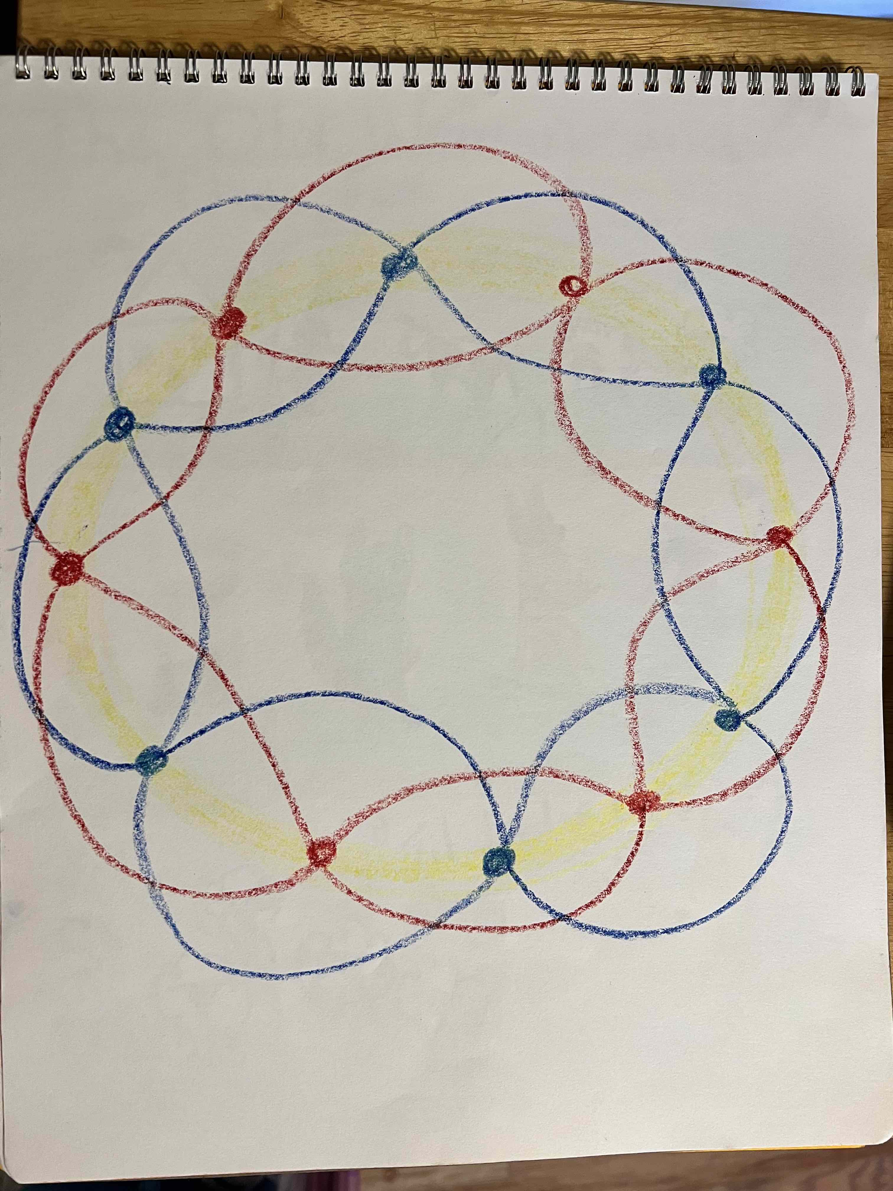 The alt text for the image provided is: "A spiral-bound notebook has colored geometric patterns on a white surface."